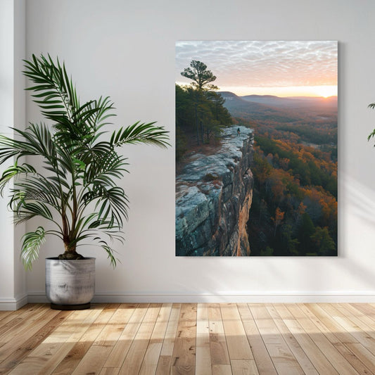 Lone hiker standing on a rocky cliff edge overlooking a forested valley at sunset with golden skies.
